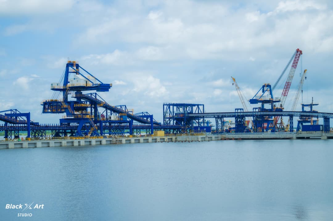 Industrial maritime port facility with large blue ship loaders and cranes situated over coastal water.